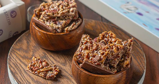 ألواح من الكاكاو البلجيكي الفاخر مغطاة بطبقة مكرملة من قطع جوز البيكان أو شرائح اللوز